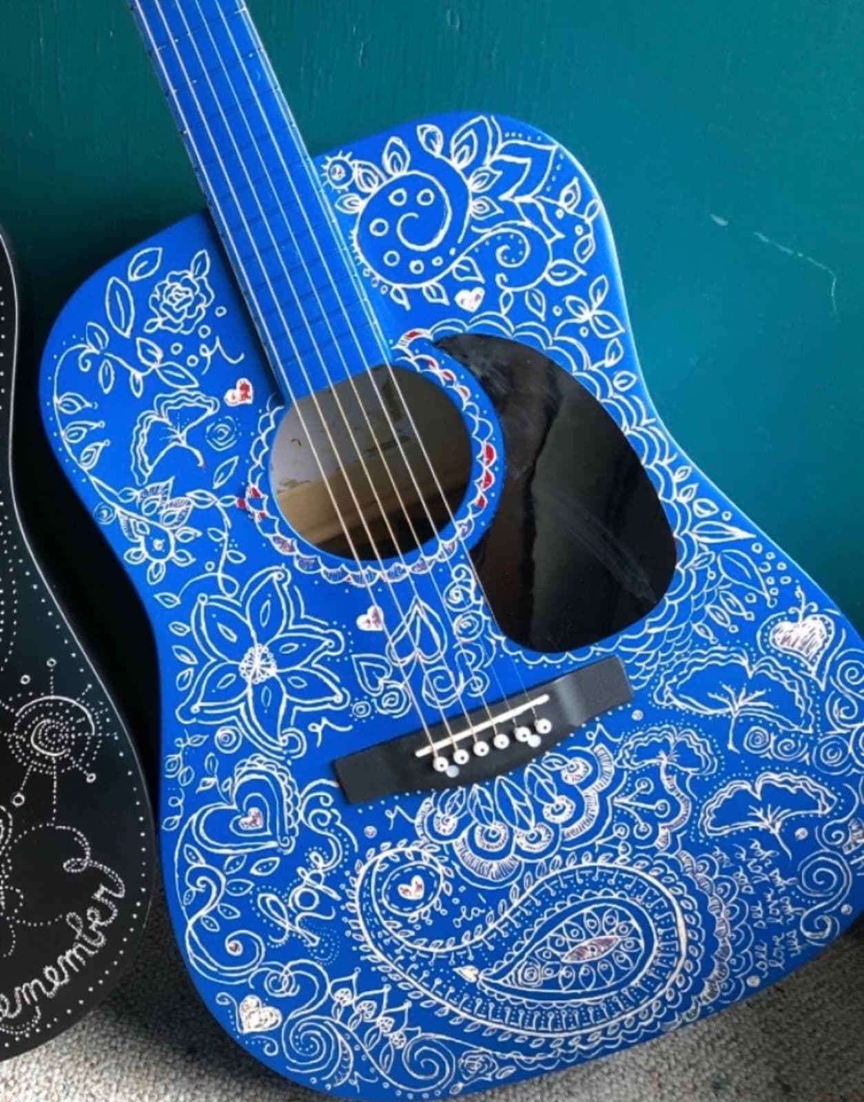 A blue acoustic guitar Susan hand-painted with flowers, hearts, and paisleys